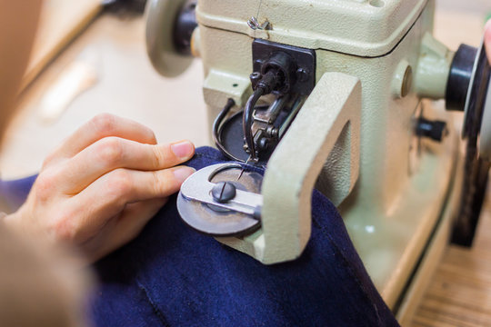 Professional male skinner, furrier using special sewing machine for stitching fur skin at atelier, workshop. Fashion and leatherwork concept