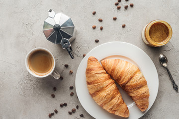 top view of cup of delicious coffee with croissants and moka pot on concrete surface with spilled coffee beans - Powered by Adobe
