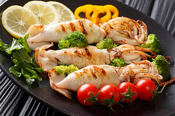 Healthy food seafood: grilled squid with fresh vegetables close-up on a plate on a wooden. horizontal