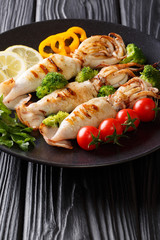 Portion of grilled squid with fresh vegetables close-up on a plate on a table. vertical