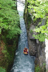 Un canoë avec des personnes dedans descend une rivière dans un canyon étroit