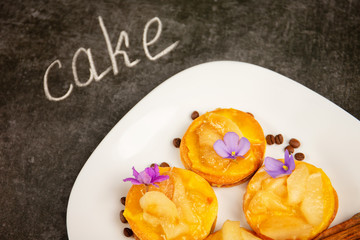 sweet cake, cinnamon and grains of coffee lie on a white plate on a gray stone background