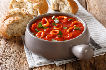 stewed squid in tomato with spices, onion, pepper and parsley close-up in a bowl and fresh bread...