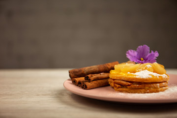 Fototapeta na wymiar sweet cake, cinnamon lie on a pink plate on a wooden table