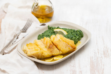 fried cod fish with spinach on dish