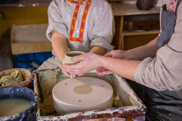 Pottery class and workshop: professional male potter working with boy and showing how to make ceramic wares in pottery studio. Handmade, education and study concept