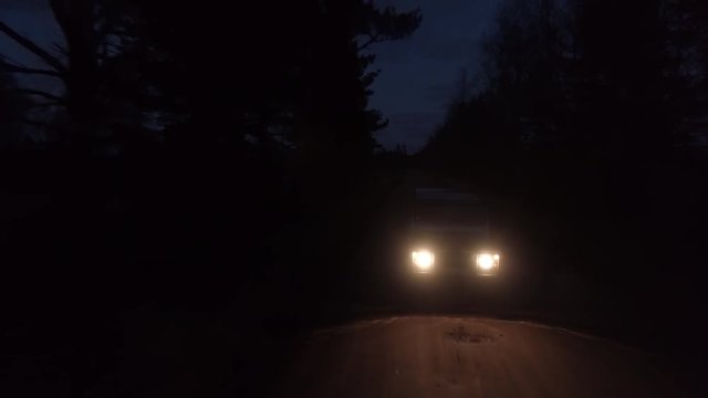 Aerial drone tracking shot of a 4x4 driving in night on a gravel road