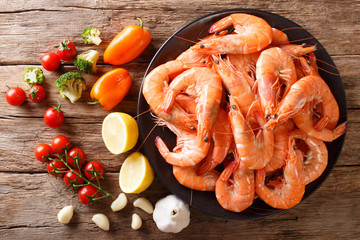 boiled tiger shrimps on a plate and fresh vegetables close-up. Horizontal  top view