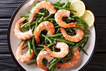 Stir fry prawns with green beans, cheese and lemon close-up on a plate. horizontal top view from above