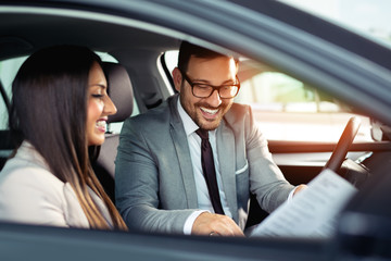 Beautiful couple is talking and smiling while sitting in their new car