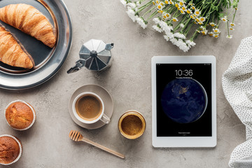 top view of coffee with pastry and tablet with ios lockscreen on concrete surface