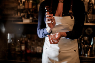 Female barman crushing a piece of ice for making a cocktail