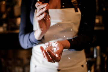 Barman girl crushing a piece of ice for making a cocktail