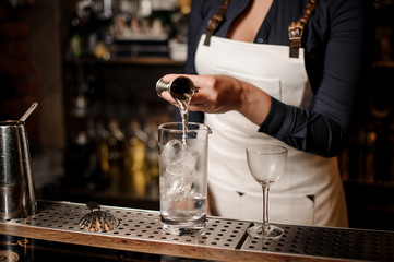 Sexy barman girl pouring vodka into a cocktail glass
