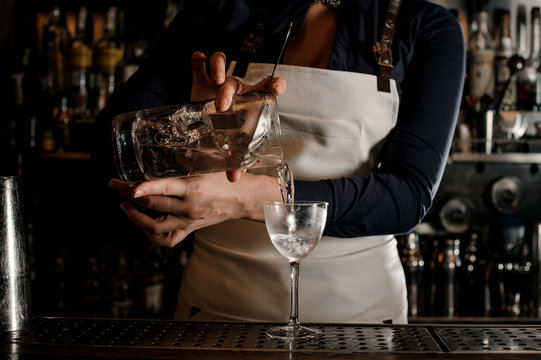 Female barman hand pouring fresh cocktail into a glass