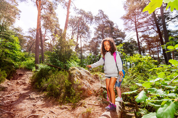 Naklejka na ściany i meble Girl walk on the log in forest wearing backpack