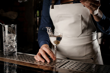 Bartender putting an olive into a cocktail glass with splash