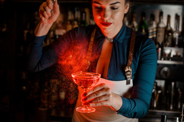 Beautiful and sexy female barman spraying bitter on the elegant cocktail glass