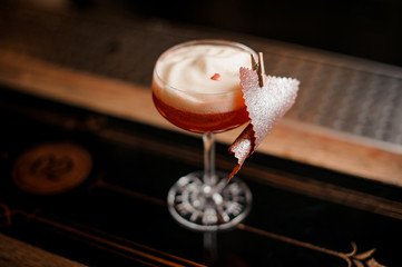 Tasty sweet alcoholic orange cocktail with foam decorated with peel