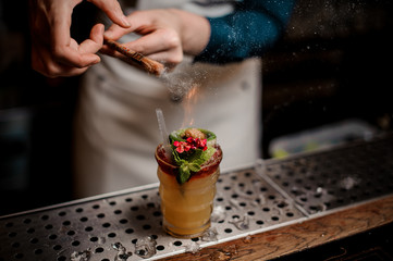 Bartender making tropical summer cocktail decorated with flowers