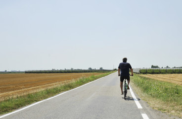 Summer vacation trip on bicycle - biker ride through gold agricultural field, Bologna, Italy