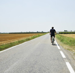 Summer vacation trip on bicycle - biker ride through gold agricultural field, Bologna, Italy