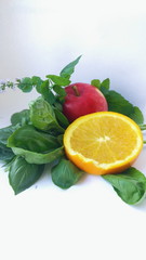 summer arrangement of apple, basil, orange and mint on a white background