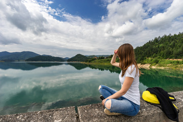 Young woman sitting and looking at lake Zaovine in Serbia