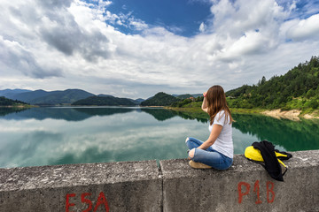 Young woman sitting and looking on Zaovine lake in Serbia