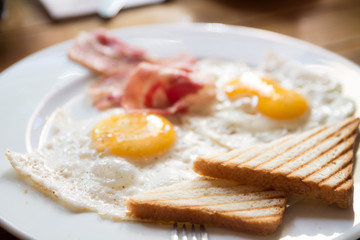 breakfast with fried eggs, bacon, toasts and cappuccino
