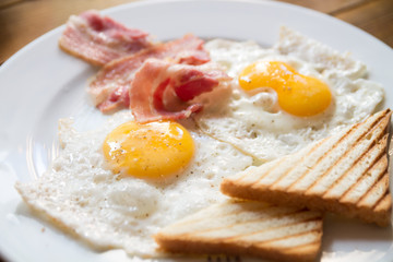 breakfast with fried eggs, bacon, toasts and cappuccino