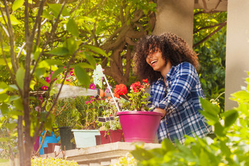 Girl spraying water with garden hose on terrace