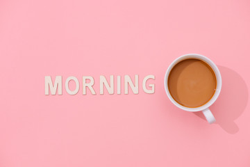 MORNING text with a cup of coffee with shadow on pink background.