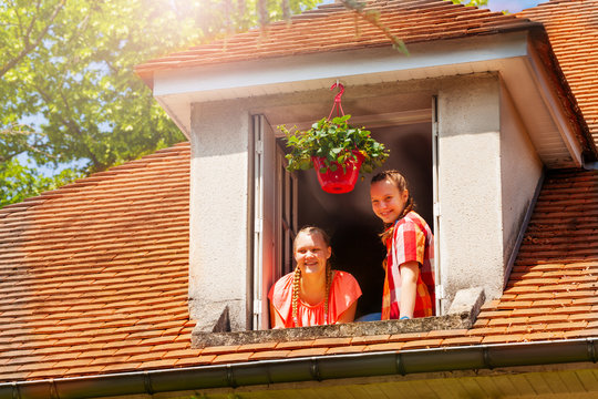 Two Girls Looking Down To Street From Attic Window