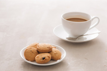 Coffee. White porcelain cup of freshly brewed coffee top view close-up arranged with  biscuits, spoon and plate on light background