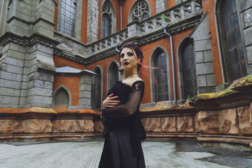 Young brunette girl in gothic style on a background architecture