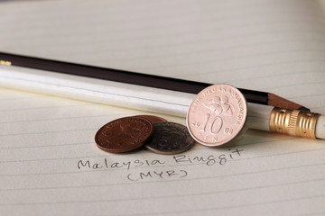 Ten sen Malaysia ringgit coin on reverse , Line image of Hibiscus rosa-sinensis and five sen with two coins of one sen, (MYR) with black and white pencil on the book. © Achisatha