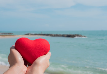 Hand with heart red shape and sea .
