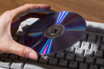 Hand Holding CD / DVD on Computer Keyboard