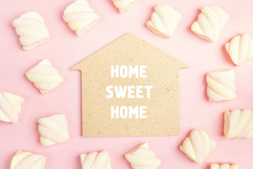 Phrase Home sweet home with spiral marshmallows on pink background.