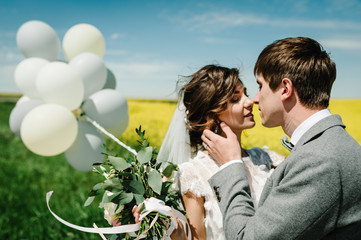 The happy bride and groom hold the balloons and stand after wedding ceremony. A newlywed couple...
