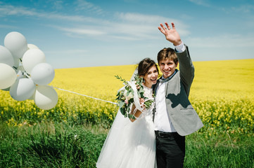 The happy bride and groom hold the balloons and stand after wedding ceremony. A newlywed couple...