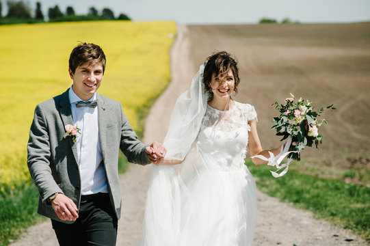 Wedding. Bride and groom holding hands and walk on the green and yellow field. wedding ceremony outdoors.