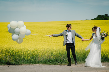 The happy bride and groom hold the balloons and walk after the wedding ceremony. The best marriage...