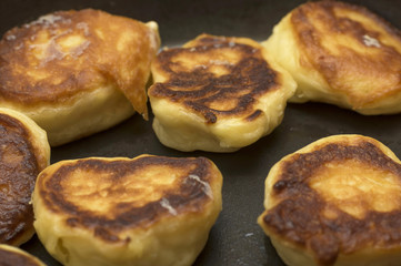 Pancakes or dumplings are fried in a frying pan on vegetable oil, close-up