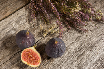 Fruits of figs and flowers of heather on an old rough wooden background.
