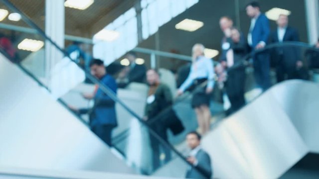 Business men are going up and down an escalator in a shopping mall or business center.