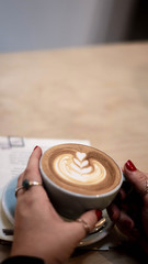 Fototapeta na wymiar Female hand holding coffee cup with menu in the background