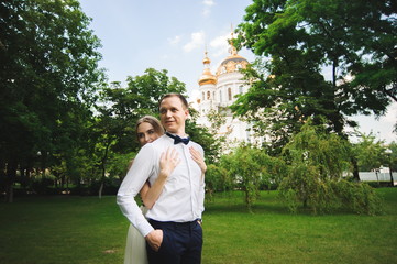 Fototapeta premium Couple in wedding attire is in the hands against the backdrop of the field at sunset, the bride and groom.