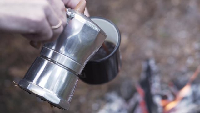 Filling enamel cup of coffee outdoors
